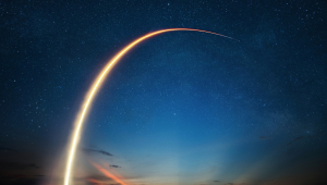 The path of a launched rocket blazing through a dark blue sky