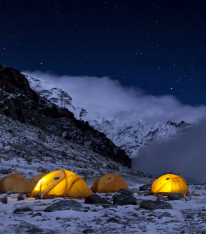 Lit-up orange tents in a snowy mountain landscape