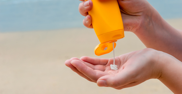 Someone's hands applying sunscreen at the beach
