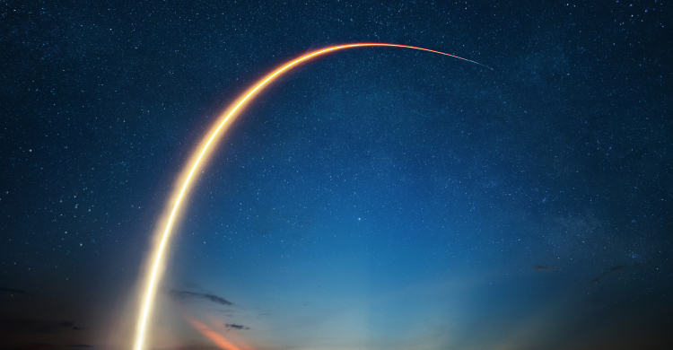 The path of a launched rocket blazing through a dark blue sky