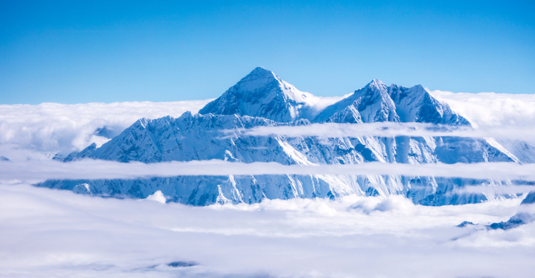 Snowy blue and white majestic mountains seen through clouds